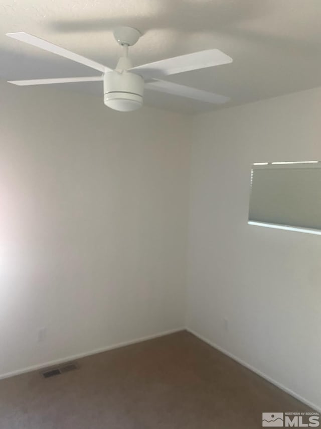 carpeted spare room with baseboards, visible vents, and a ceiling fan