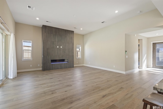 unfurnished living room featuring a tiled fireplace and light wood-type flooring