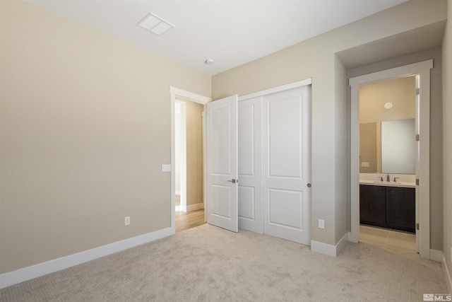 unfurnished bedroom with sink, light colored carpet, and a closet