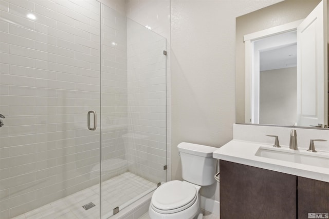 bathroom featuring vanity, a shower with door, and toilet