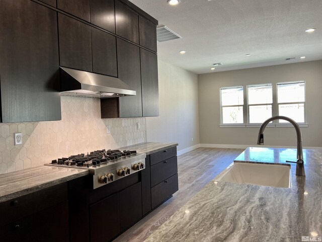 kitchen with a textured ceiling, stainless steel appliances, sink, and light stone countertops