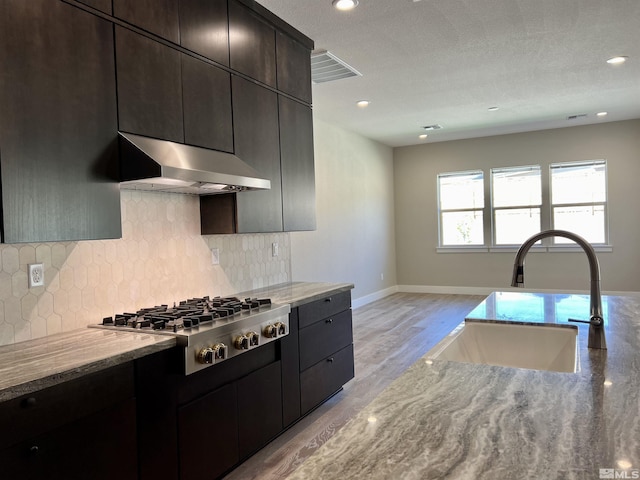 kitchen featuring sink, ventilation hood, light stone countertops, and stainless steel gas cooktop