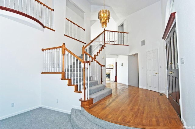 entryway featuring a towering ceiling, hardwood / wood-style flooring, and a chandelier