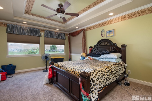 carpeted bedroom with ornamental molding, a tray ceiling, and ceiling fan