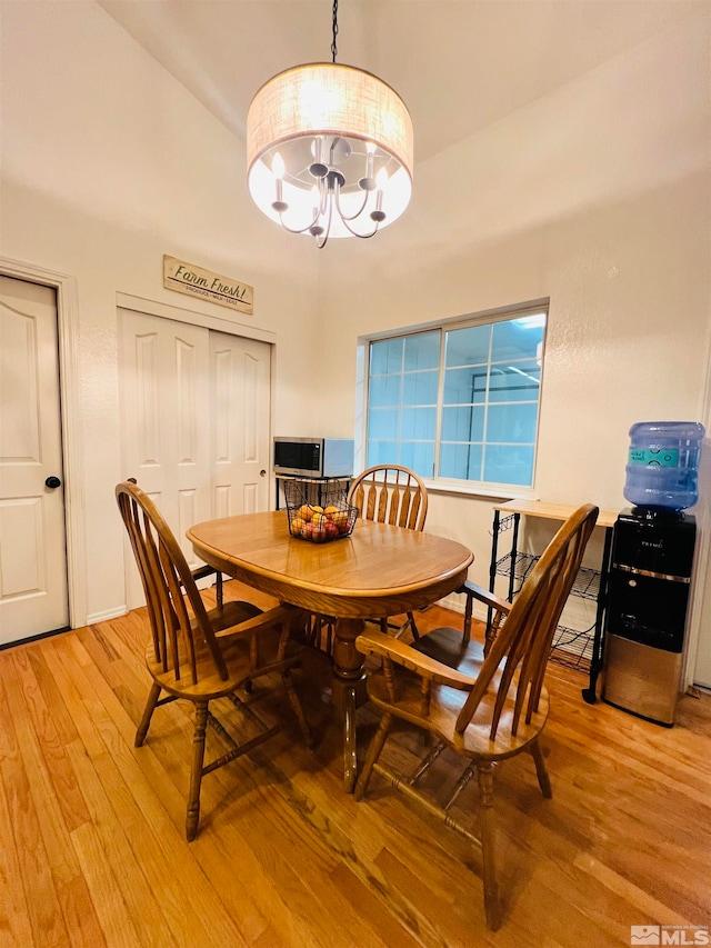 dining area with light wood-type flooring and an inviting chandelier