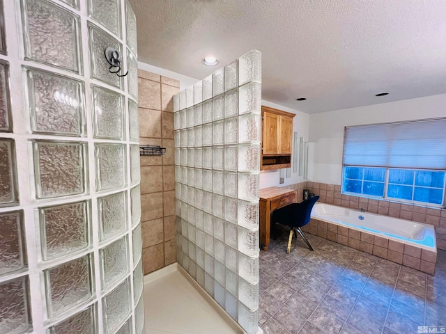 bathroom featuring tile walls, a textured ceiling, a relaxing tiled tub, and tile patterned flooring