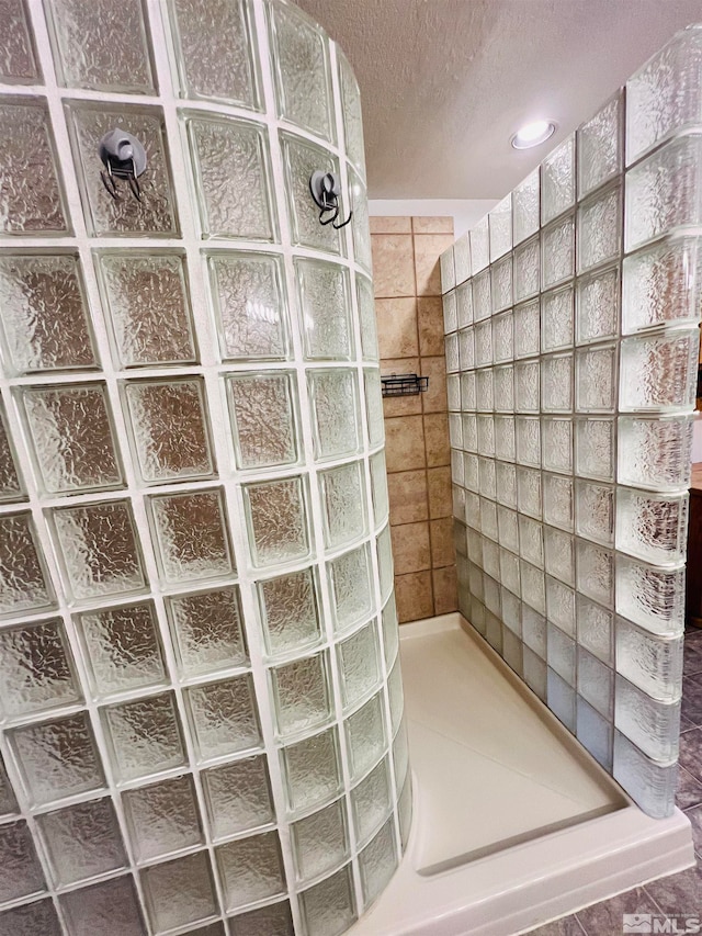 interior space with a tile shower and a textured ceiling