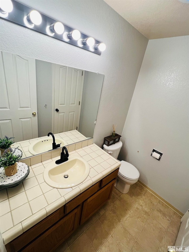 bathroom featuring vanity, tile patterned flooring, and toilet