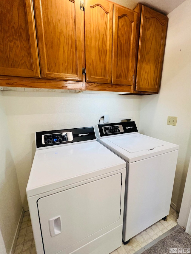 laundry area with washer and dryer, light tile patterned floors, and cabinets