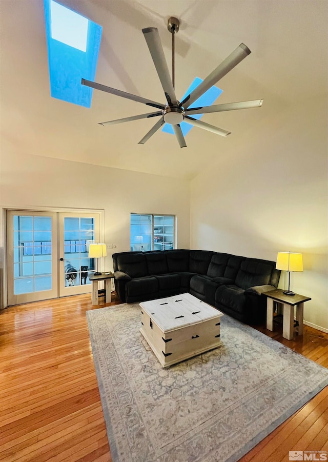 living room featuring ceiling fan, light wood-type flooring, and a skylight