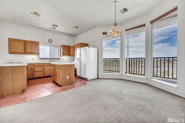 kitchen featuring light tile patterned flooring, white refrigerator with ice dispenser, a center island, and a wealth of natural light