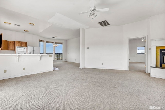 unfurnished living room featuring ceiling fan, light colored carpet, and plenty of natural light