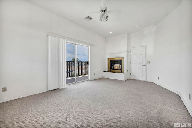 unfurnished living room featuring ceiling fan, light carpet, and a high ceiling