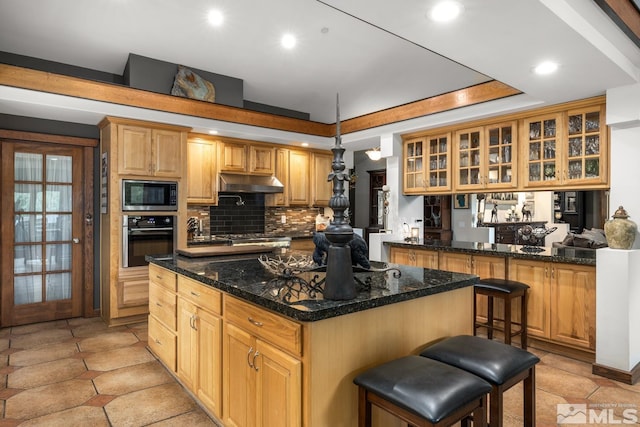 kitchen featuring light tile patterned floors, a kitchen bar, stainless steel microwave, tasteful backsplash, and oven