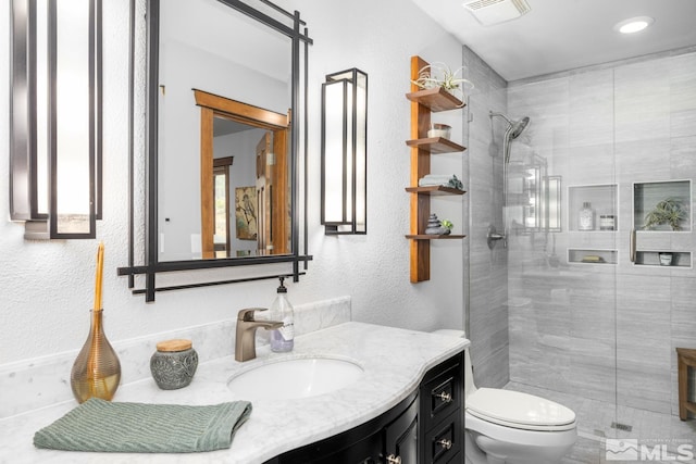 bathroom with toilet, an enclosed shower, and vanity