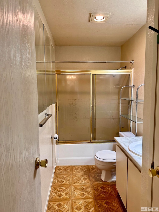 full bathroom with shower / bath combination with glass door, a textured ceiling, toilet, vanity, and parquet floors