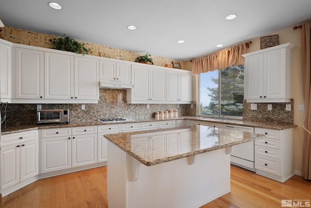 kitchen with white dishwasher, light wood-type flooring, a center island, and white cabinets