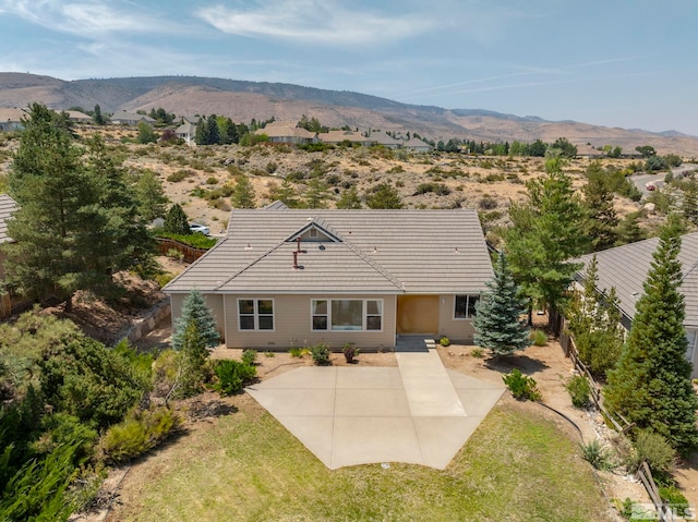 back of property with a mountain view and a patio