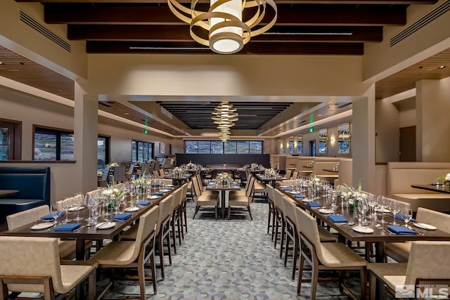 dining space with a notable chandelier, beam ceiling, and a high ceiling