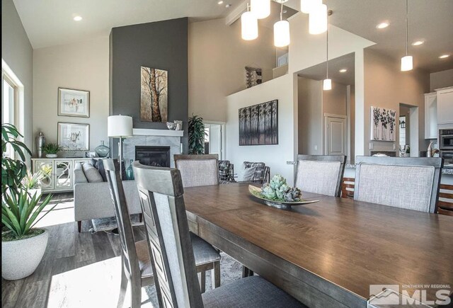 living room with a tiled fireplace, hardwood / wood-style floors, and high vaulted ceiling