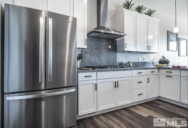 kitchen featuring dark wood finished floors, decorative backsplash, appliances with stainless steel finishes, wall chimney range hood, and white cabinetry