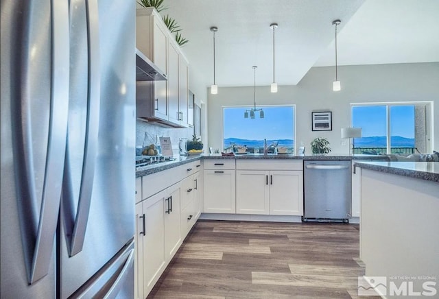 kitchen with appliances with stainless steel finishes, white cabinetry, hardwood / wood-style flooring, and pendant lighting