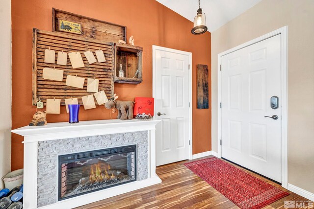 entrance foyer featuring dark wood-style floors, baseboards, and a stone fireplace