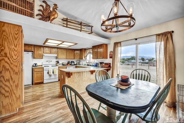 dining area with lofted ceiling, an inviting chandelier, and light wood-style floors