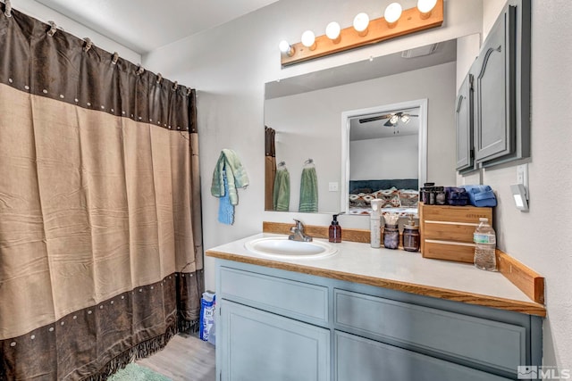 bathroom with wood finished floors, connected bathroom, vanity, and ceiling fan