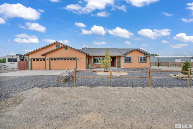 view of front facade with driveway, an attached garage, and fence