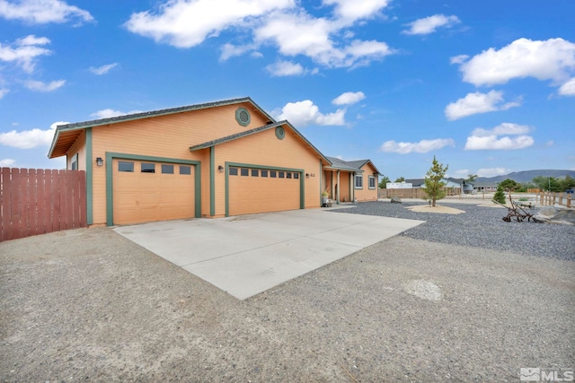 view of front of house featuring driveway, an attached garage, and fence