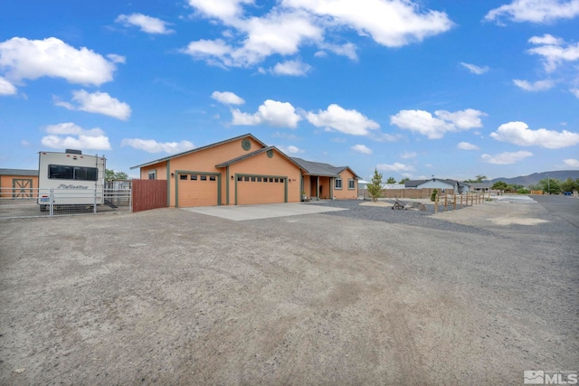 view of front facade with driveway, an attached garage, fence, and a mountain view