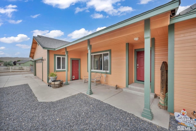 exterior space with driveway, a shingled roof, an attached garage, and fence