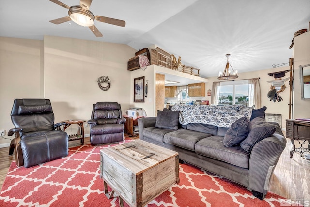 living room with lofted ceiling, ceiling fan with notable chandelier, wood finished floors, and baseboards