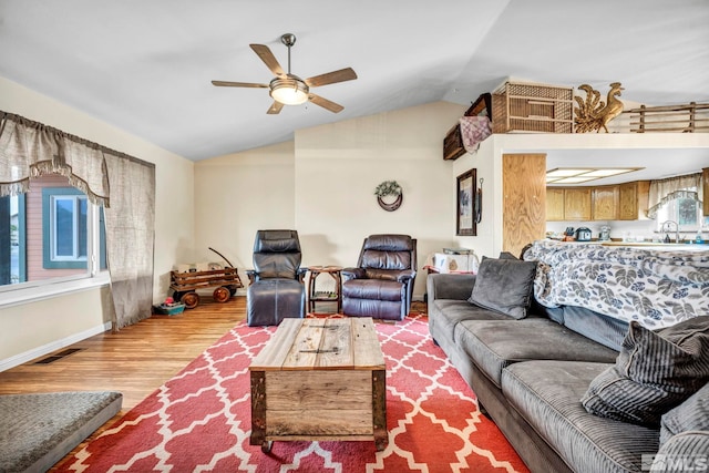 living room with light wood finished floors, visible vents, a ceiling fan, vaulted ceiling, and baseboards