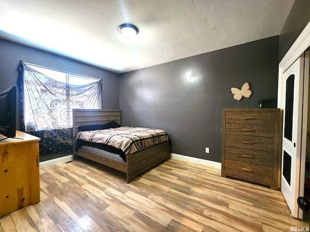 bedroom featuring light wood finished floors and baseboards