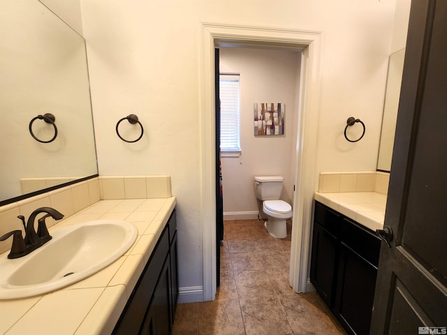 bathroom featuring vanity, toilet, and baseboards