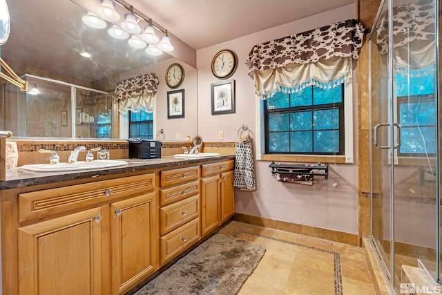 full bath with double vanity, a sink, and a shower stall