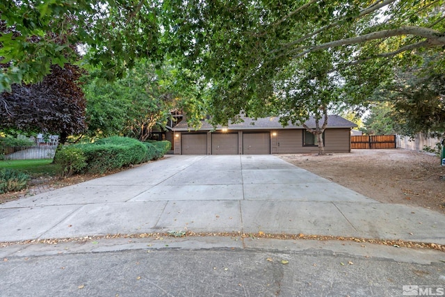 view of front of home featuring driveway, an attached garage, and fence