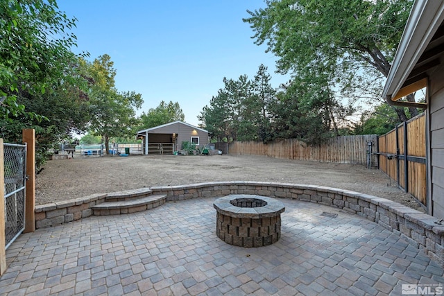 view of patio / terrace featuring a fenced backyard, an outdoor structure, and a fire pit