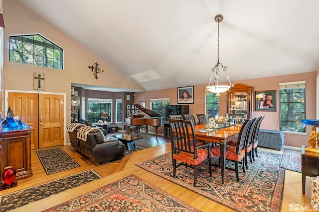 dining room with a healthy amount of sunlight, high vaulted ceiling, and light hardwood / wood-style floors