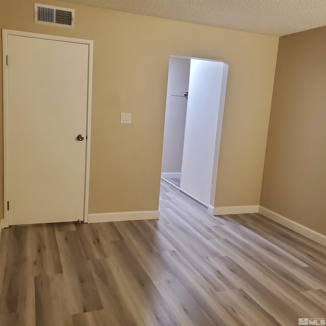 unfurnished room featuring a textured ceiling and light wood-type flooring