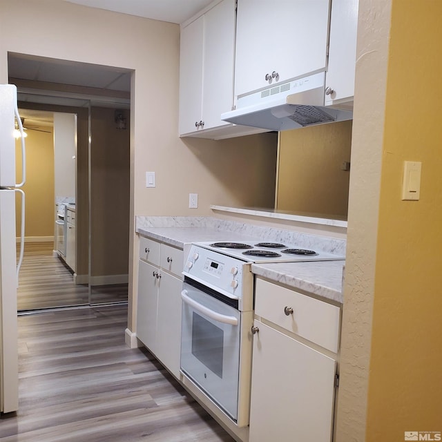 kitchen with white cabinetry, white appliances, and light hardwood / wood-style floors