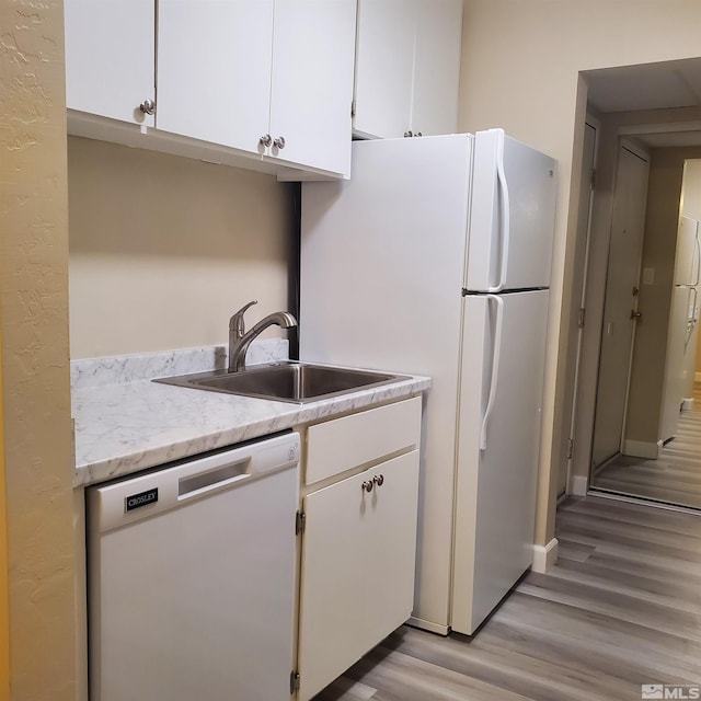 kitchen with white cabinetry, sink, white appliances, and light hardwood / wood-style floors