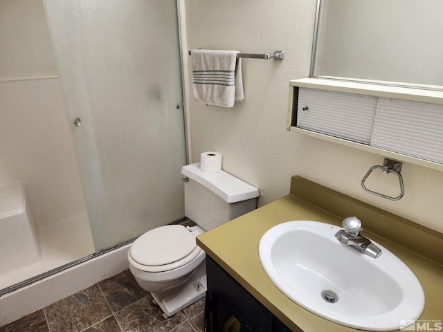 bathroom with stone finish floor, a shower stall, toilet, and vanity