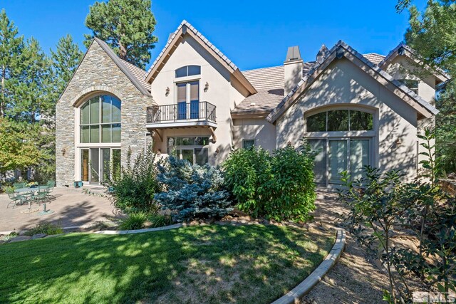 rear view of property featuring a balcony and a lawn