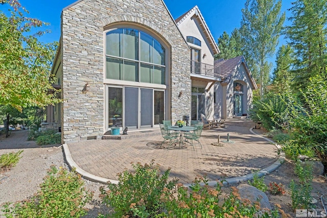 rear view of property featuring a balcony and a patio