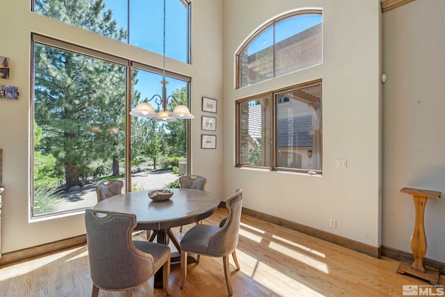 dining area featuring a high ceiling, a notable chandelier, and light wood-type flooring