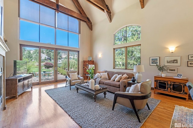 living room with high vaulted ceiling, light wood-type flooring, and beam ceiling