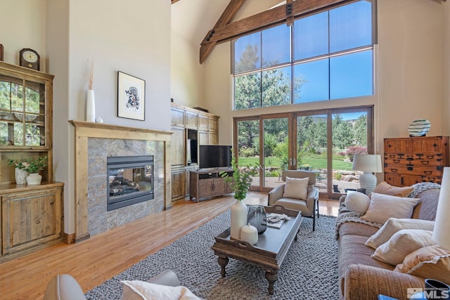 living room with a fireplace, beam ceiling, high vaulted ceiling, and light wood-type flooring